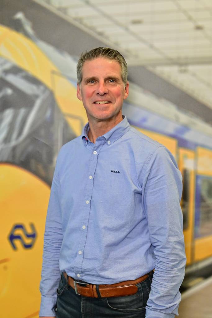 Leonard de Roos met op de achtergrond een NS trein.